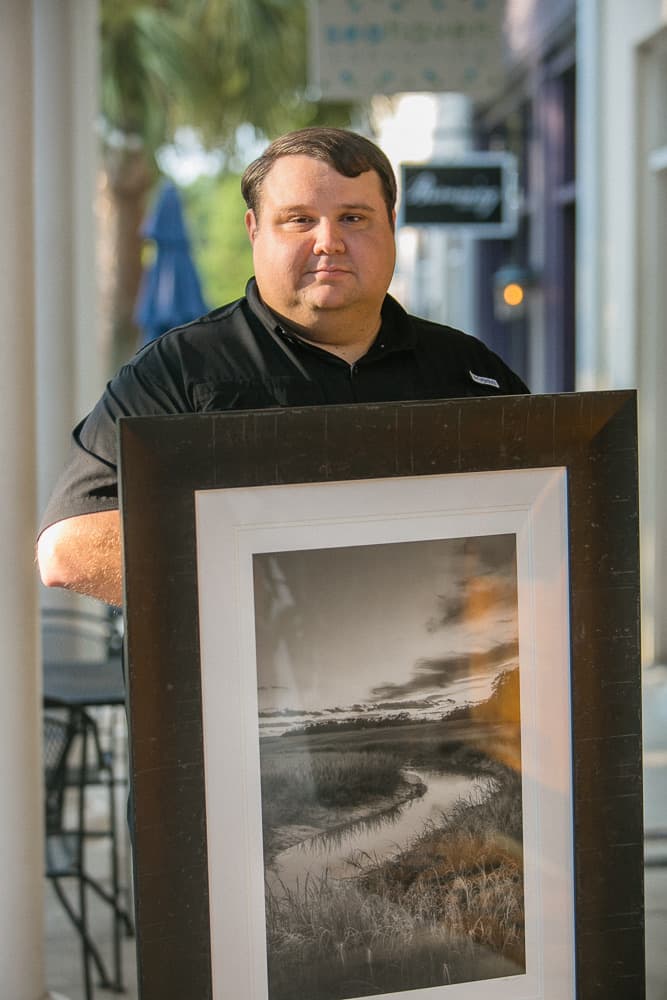 Andrew Branning holding a framed black and white landscape print